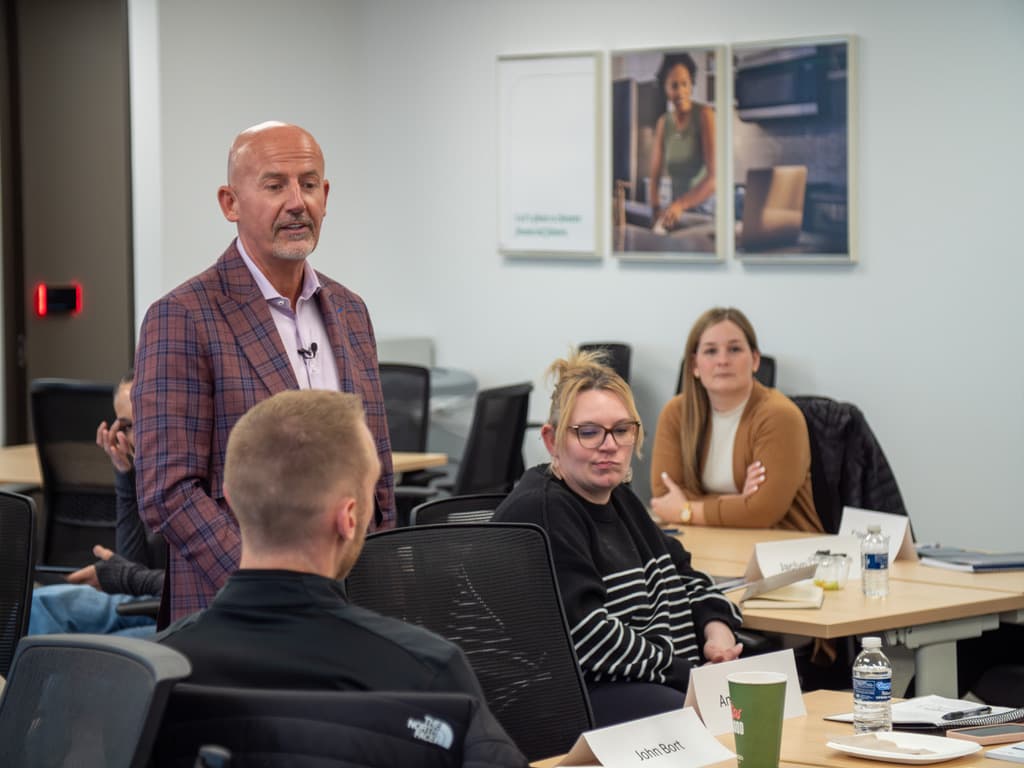 Steve Lowisz with DEC emerging leaders gathered around tables during a session